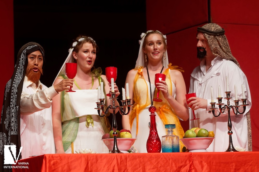 Four people at an altar raising red colored wine goblets.
