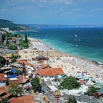 Beach town with rows of umbrellas on the beach in front of orange roof homes.