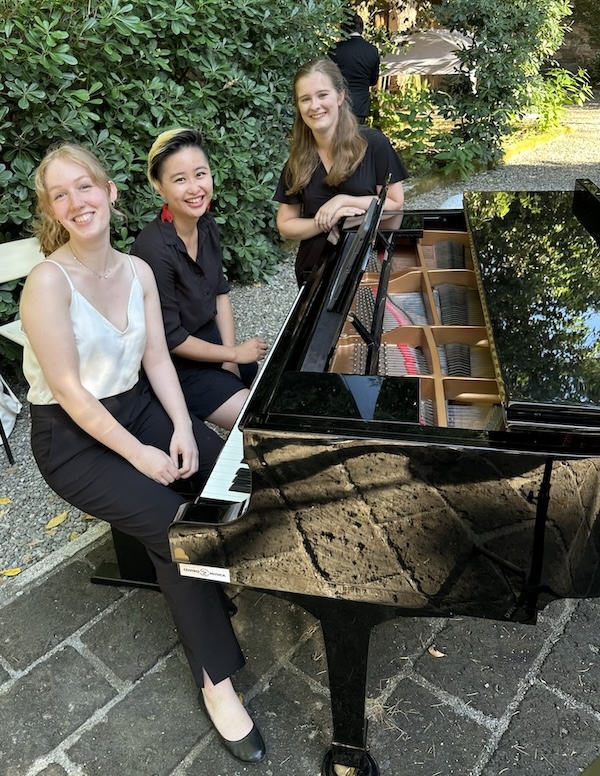 Three people sitting at a piano