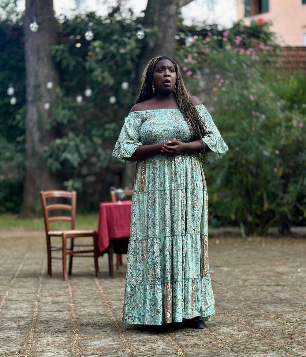 Woman dressed in blue singing outside.